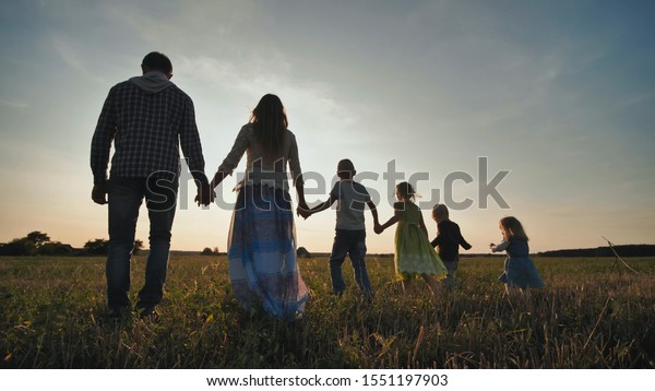 A\
large family of six people walk on the floor at\
sunset.