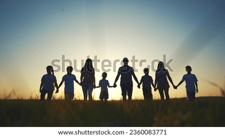 large family walks across field holding hands. happy family childhood dream concept. family walks across the field on the grass at sunset and lifestyle hold each other's hands dark silhouettes
