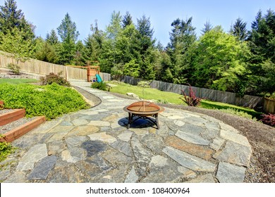 Large Fenced Backyard With Stone And Fire Pit With Trees.