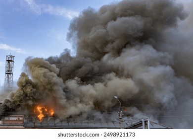 A large fire is burning in the sky, with smoke billowing out of the top of a building - Powered by Shutterstock