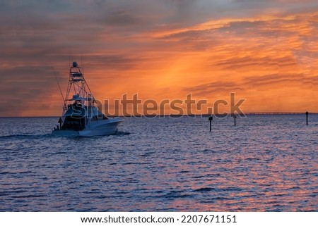 Large fishing troller heading out at sunset on the Gulf of Mexico in Destin, located in the Panhandle of Florida.