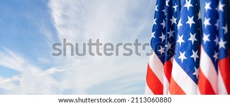 Large flag of usa waving in the wind against the sky with clouds on sunny day.