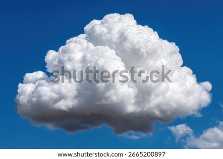 A large, fluffy cumulus cloud dominates a vibrant blue sky.  Its bright white form contrasts sharply with the deep blue background.