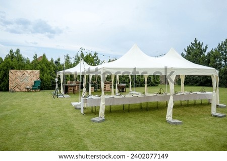 Large folding white tents in a wedding party. Place for wedding banquet outdoors.