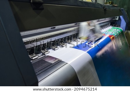 Large format inkjet printer machine working on vinyl paper in workplace
