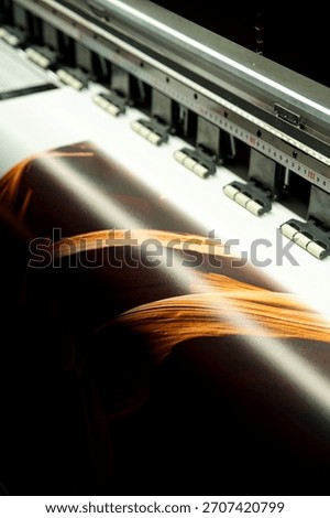 Large format inkjet printer printing colorful graphic on vinyl material in commercial print shop	