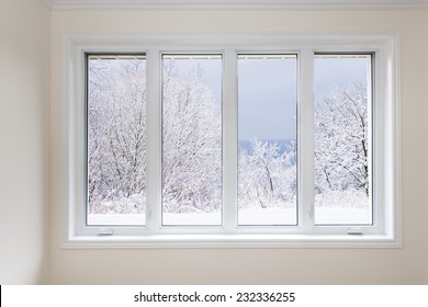 Large four pane window looking on snow covered trees in winter