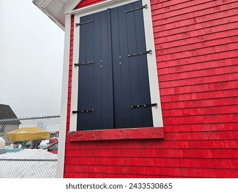 A large frame that could  be a window or a door with shutters on the side of a building.
