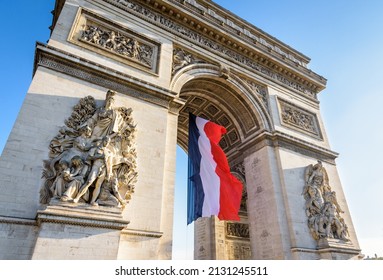 A large french flag is fluttering in the wind under the vault of the Arc de Triomphe in Paris, France.