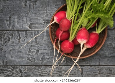 Large fresh radishes in a clay bowl on a wooden table. Healthy and healthy, natural food.