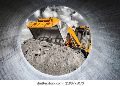 A large front loader pours sand into a pile at a construction site. Transportation of bulk materials. Construction equipment. Bulk cargo transportation. Excavation. View from a large concrete pipe - Shutterstock ID 2198775073