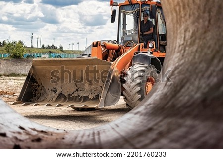 A large front loader pours sand into a pile at a construction site. Transportation of bulk materials. Construction equipment. Bulk cargo transportation. Excavation