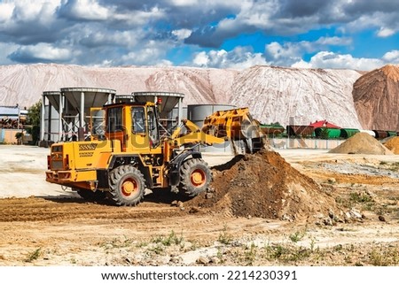 A large front loader pours sand into a pile at a construction site. Transportation of bulk materials. Construction equipment. Bulk cargo transportation. Excavation
