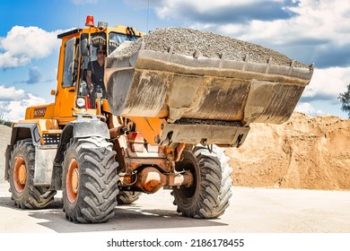 A Large Front Loader Transports Crushed Stone Or Gravel In A Bucket At A Construction Site Or Concrete Plant. Transportation Of Bulk Materials. Construction Equipment. Bulk Cargo Transportation