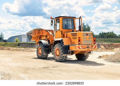 A Large Front Loader Transports Crushed Stone Or Gravel In A Bucket At A Construction Site Or Concrete Plant. Transportation Of Bulk Materials. Construction Equipment. Bulk Cargo Transportation