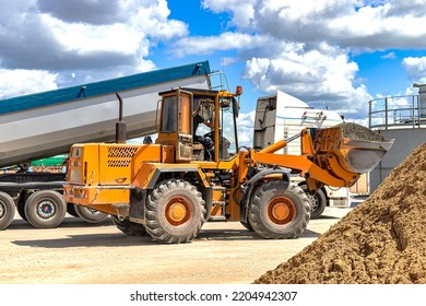 A Large Front Loader Transports Crushed Stone Or Gravel In A Bucket At A Construction Site Or Concrete Plant. Transportation Of Bulk Materials. Construction Equipment. Bulk Cargo Transportation