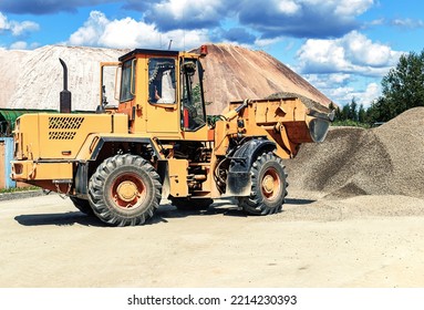 A Large Front Loader Transports Crushed Stone Or Gravel In A Bucket At A Construction Site Or Concrete Plant. Transportation Of Bulk Materials. Construction Equipment. Bulk Cargo Transportation