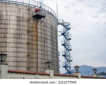 Large Fuel Tanks. Tanks And Ladders Of The Tank Farm. The Gloomy Atmosphere Of An Industrial Area. Oil Storage
