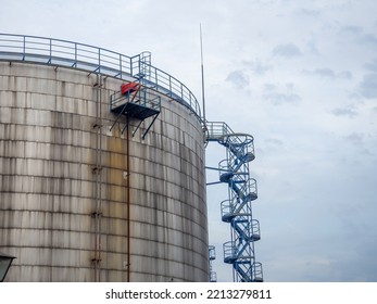 Large Fuel Tanks. Tanks And Ladders Of The Tank Farm. The Gloomy Atmosphere Of An Industrial Area. Oil Storage
