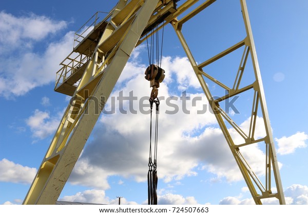 A large gantry crane made of metal colored yellow
in the background of a bright blue sky with clouds close-ups moves
the cargo