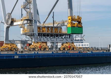 Large gantry cranes moving containers in ‘ship to shore’ logistics  into container river barge on the Maasvlakte, europoort, Rotterdam, the Netherlands