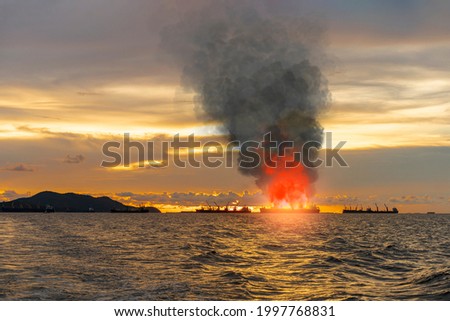 Large general cargo ship for logistic import export goods and other anchored at the offshore sea horizon the explosion and had a lot of fire and smoke at sea in evening
