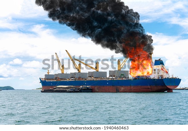 Large general cargo ship for logistic import export\
goods and other the explosion and had a lot of fire and smoke at\
sea in bright day