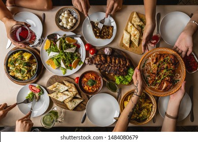 large and generously covered with delicious dishes table, covered with a tablecloth on which there are various delicious dishes of Ukrainian cuisine: fried ribs, borsch, salads, cheese - Powered by Shutterstock