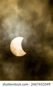 A large, glowing moon is seen through a cloudy sky. The moon is the only bright object in the image, and it is surrounded by a dark, hazy atmosphere. Scene is mysterious and somewhat ominous