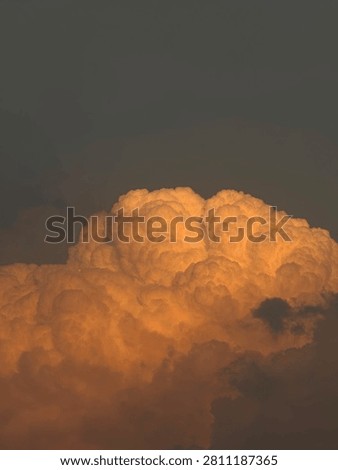 Large glowing orange cloud with rich golden tones, creating a dramatic and captivating natural scene during sunset.