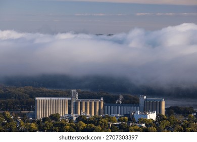 A large grain elevator with several silos in a town along the Mississippi River.