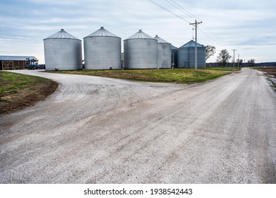 Large Grain Storage Bins On Farm Next To Gravel Country Road In Rural America. Farming, Farmers, Food, Crops, Storage, Silos, Silo, Corn, Grain, Soybean, Containers, Store, Dry