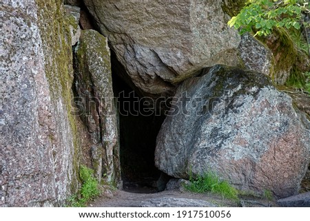 Large gray stones frame the entrance to the cave in the Monrepos Park in the city of Vyborg.