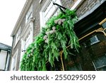 Large, green artificial flowers and branches hanging from traditional English pub.