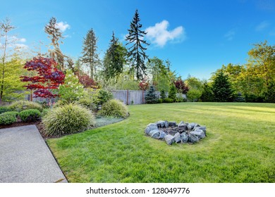 Large Green Backyard With Beautiful Landscape And Fire Pit.