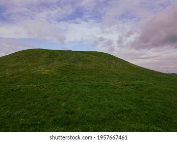 A Large Green Burial Mound Under A Cloudy Sky In Weymouth, Dorset, UK