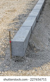 Large Grey Granite Curb Stone And String With Stakes To Level At Road Construction Site. Selective Focus.