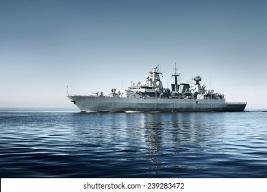 Large grey modern warship sailing in still water. Clear blue sky. Baltic sea, Germany. Global communications, international security theme. Panoramic image