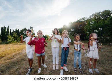 A large group of cheerful children play in the Park and inflate soap bubbles. Games in a children's camp - Powered by Shutterstock