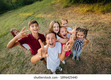 A large group of cheerful children sit on the grass in the Park and smile. Games in a children's camp - Powered by Shutterstock