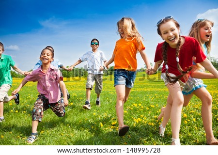 Large group of children running in the dandelion spring field