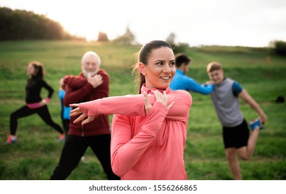 Large Group Of Fit And Active People Stretching After Doing Exercise In Nature.