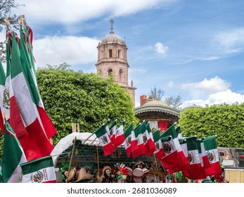 A large group of flags are displayed in front of a church. The flags are of different colors. Historic center of Queretaro City, decorations and traditions to celebrate Mexico's Independence Day, colo