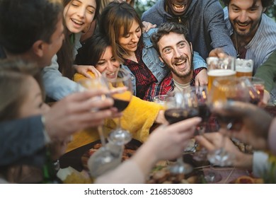 A large group of friends celebrates a birthday by crowding around the birthday boy, clinking glasses of wine and beer amidst hilarity, happiness and laughter - lifestyle - Shutterstock ID 2168530803
