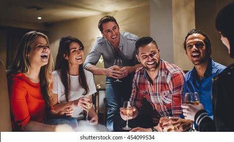 Large Group Of Friends Enjoying A Glass Of Wine Together In A Bar. 