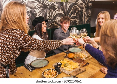 Large Group Of Friends Raising Their Glasses For A Toast At A Dinner Party