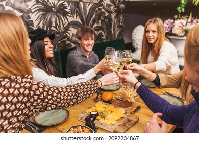 Large Group Of Friends Raising Their Glasses For A Toast At A Dinner Party.