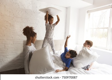 A large group of friends taking goog time on bed with pillow fight - Powered by Shutterstock