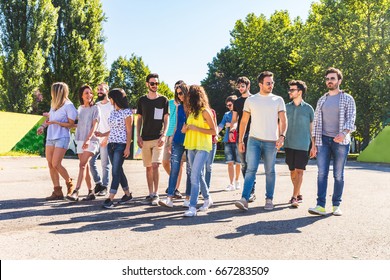 Large Group Of Friends Walking Together At Park. Multi Ethnic Group Of People Talking And Walking On A Sunny Day. Friendship And Lifestyle Concepts