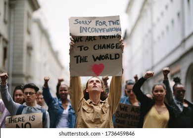 Large group of global warming protestors march up the street. Group of demonstrators making protest about climate change.